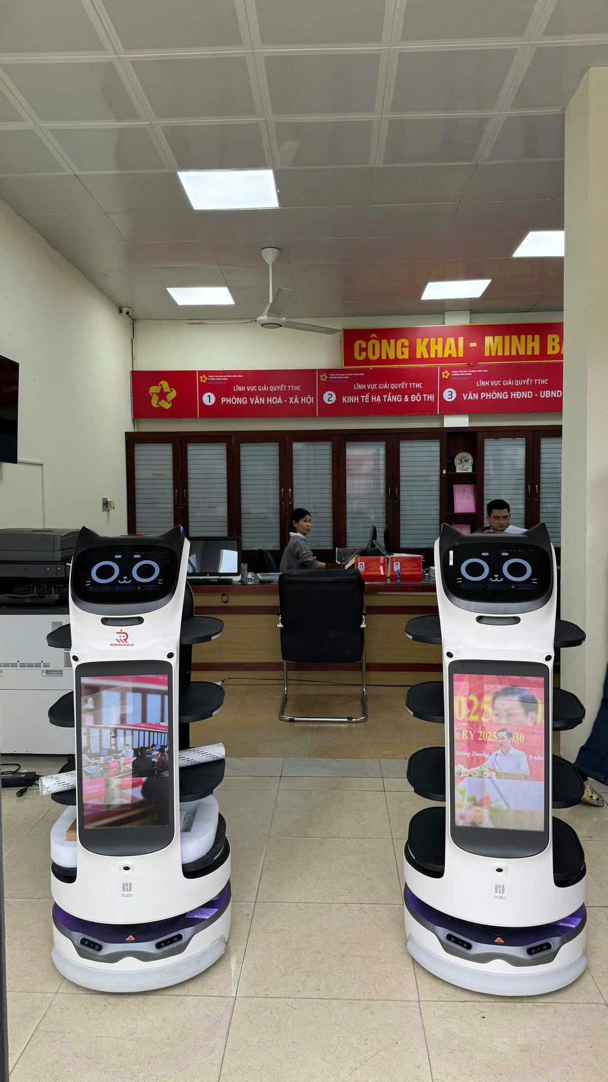Hai robot Roboworld đón tiếp và hướng dẫn công dân tại quầy giải quyết thủ tục hành chính, Trung tâm Phục vụ Hành chính công phường Mông Dương, Quảng Ninh